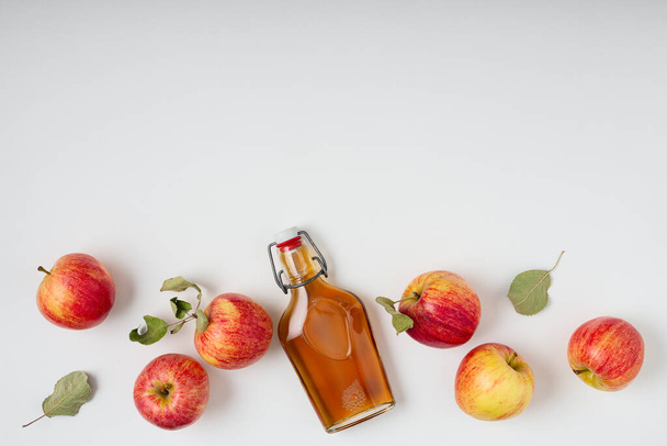 Fresh ripe apples and apple cider vinegar. Apple cider in a glass bottle and fresh apples. Light background. Top view. Copy space of your text. - Photo, image