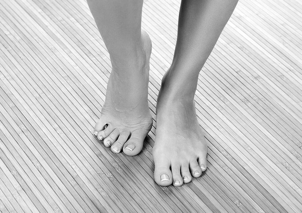 Piękne kobiece stopy na drewnianej podłodze, ujęcie z bliska - Zdjęcie, obraz