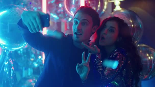 Leuk stel dat selfie maakt in de nachtclub. Man en vrouw maken gebaren op het feest - Video
