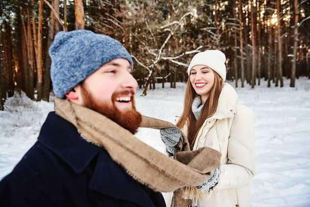 Зимние весёлые пары играют вместе во время зимних каникул на свежем воздухе в снежном лесу. Парень и девушка улыбаются и смеются. Выходные за городом. Рождественское утро, провести рождественские каникулы вместе. - Фото, изображение