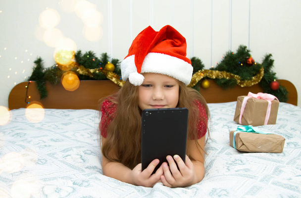 Vánoční online gratulace. Usmívající se dívka žena pomocí mobilního tabletu pro videohovory přátelé a rodiče.Vánoční on-line nakupování, práce a vzdělávání.  - Fotografie, Obrázek