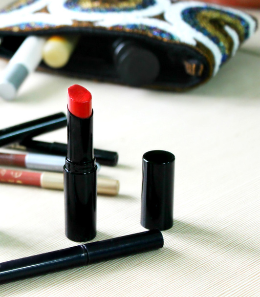 Batom vermelho, lápis e outros cosméticos na mesa
 - Foto, Imagem