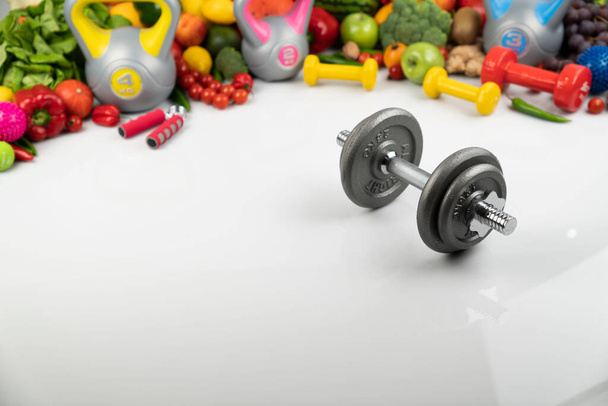 Fitness koncepció. Egészséges táplálkozás: gyümölcsök és zöldségek. Felszerelés fitnesz feladatokhoz: mérőgép és súlyzók. Fehér háttér. - Fotó, kép