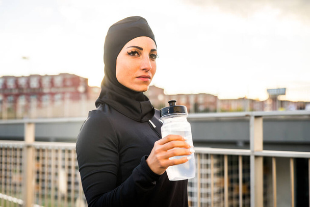 Chica deportiva musulmana con entrenamiento corporal en forma al aire libre - Hermosa mujer con hiyab haciendo algunos ejercicios deportivos, conceptos sobre salud, estilo de vida y entrenamiento funcional - Foto, Imagen