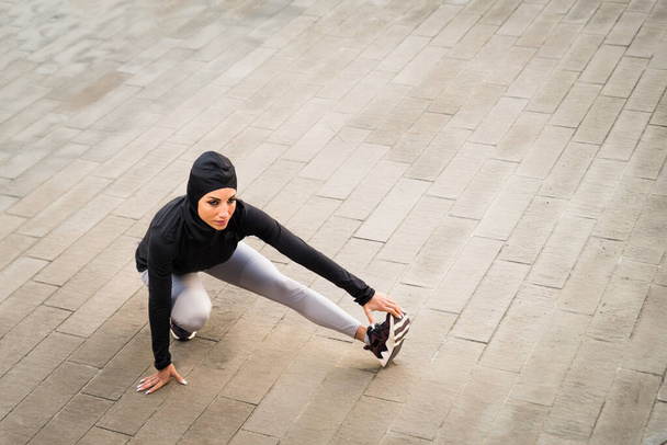 Мусульманская спортивная девушка с тренировкой тела снаружи - красивая женщина с хиджабом делает некоторые спортивные упражнения, концепции о здоровье, образе жизни и функциональных тренировок - Фото, изображение