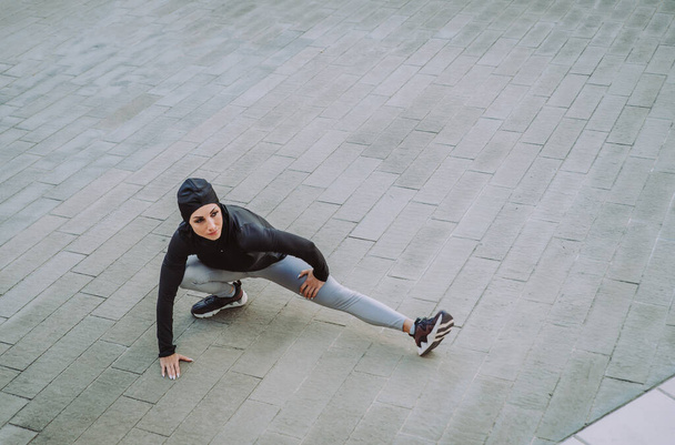 Muszlim sportos lány fitt testedzés kívül - Gyönyörű nő hidzsáb csinál néhány sport gyakorlatok, fogalmak az egészségügyi, életmód és a funkcionális képzés - Fotó, kép