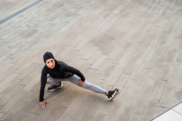 Chica deportiva musulmana con entrenamiento corporal en forma al aire libre - Hermosa mujer con hiyab haciendo algunos ejercicios deportivos, conceptos sobre salud, estilo de vida y entrenamiento funcional - Foto, imagen
