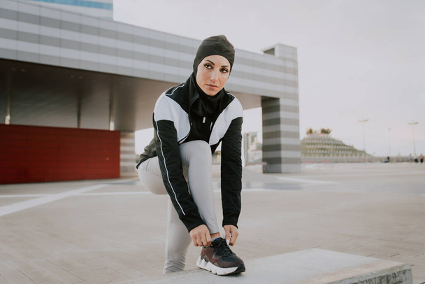 Muslim sportive girl with fit body training outside - Beautiful woman with hijab doing some sport exercises, concepts about health, lifestyle and functional training - Valokuva, kuva