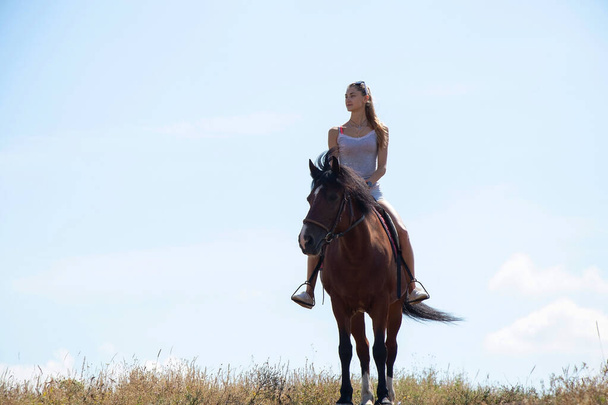 chica sentada a caballo contra el cielo en un día soleado - Foto, imagen
