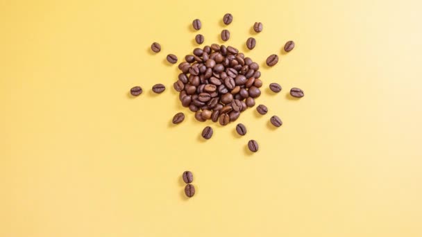 Coffee beans on a yellow background are folded into the shape of the sun, cup and steam. Stop motion. Creative concept of morning, wake up, breakfast, coffee. - Footage, Video