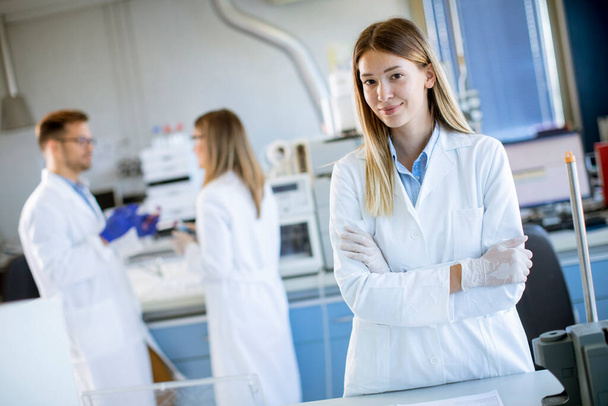 Beyaz laboratuvar önlüklü genç kadın bilim adamı biyomedikal laboratuarda duruyor. - Fotoğraf, Görsel