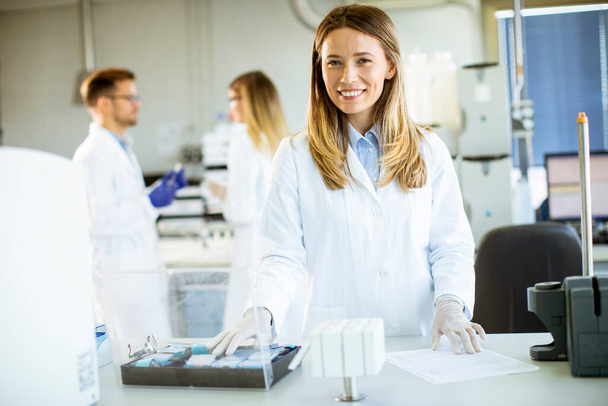 Joven científica con bata blanca de laboratorio parada en el laboratorio biomédico - Foto, Imagen