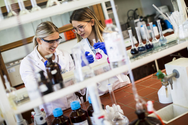 Investigadoras lindas en bata blanca de laboratorio trabajando en el laboratorio - Foto, Imagen