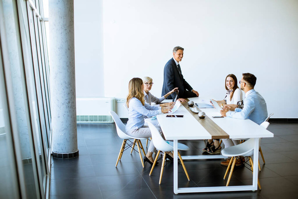 Gruppe von Geschäftsleuten mit jungen Erwachsenen und Seniorenkollegin beim Treffen im modernen, hellen Büroinnenraum - Foto, Bild