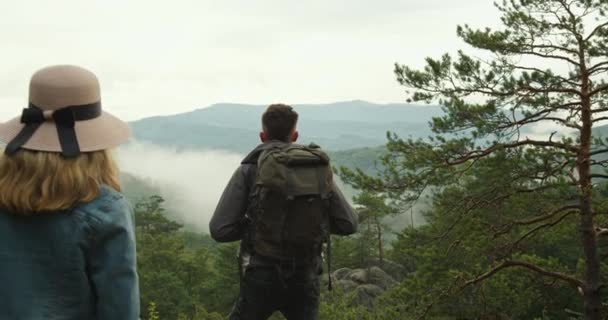 Η γυναίκα πλησιάζει τον άντρα. Στέκονται στην κορυφή ενός γκρεμού και κοιτάζουν τη φύση. Πεζοπορία στα βουνά. 4K DCI - Πλάνα, βίντεο