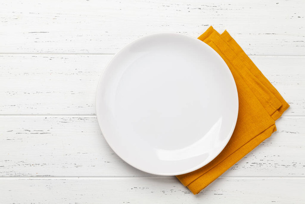 Wit leeg bord en servet op houten tafel. Bovenaanzicht plat lag met ruimte voor uw maaltijd - Foto, afbeelding