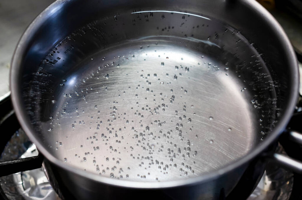 Kookwater in roestvrijstalen pan in keuken - Foto, afbeelding