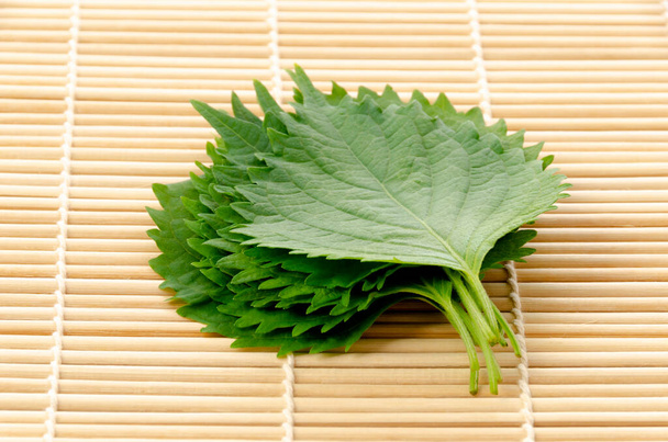 Friss zöld shiso (perilla frutescens) vagy obalevél bambusz hengerelt szőnyegen. - Fotó, kép
