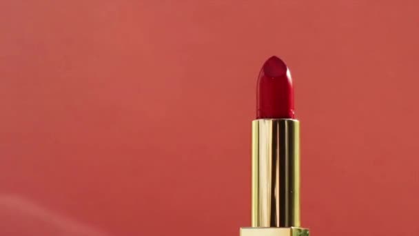 Шикарная красная помада в золотой трубке и яркие вспышки света, роскошный косметический продукт и праздничная косметика для бренда красоты - Кадры, видео