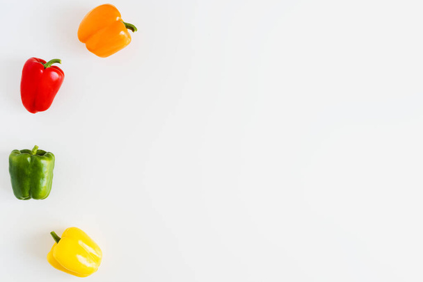 Fondo simple con pimientos coloridos en la mesa de la cocina blanca. Capsicum de color naranja, rojo, verde y amarillo - Foto, imagen