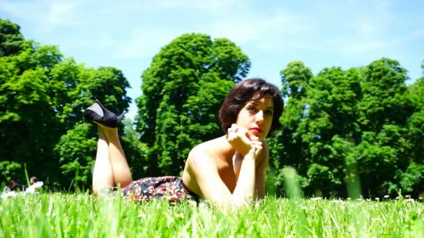 hermosa chica con el pelo corto acostado en el jardín público en parma - Metraje, vídeo