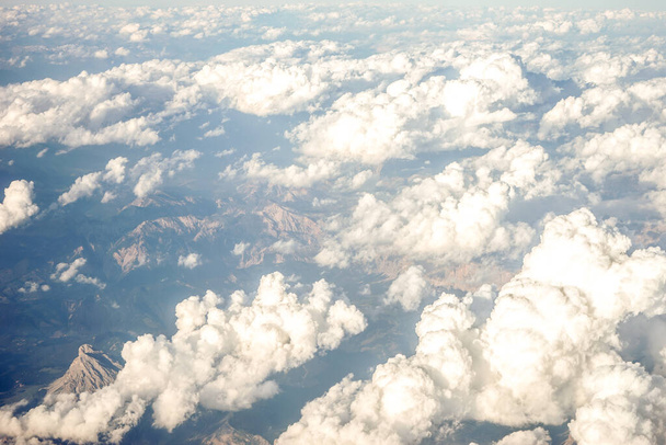 Chmury nad ośnieżonymi Alpami Austriackimi widziane z okna samolotu, Europa - Zdjęcie, obraz