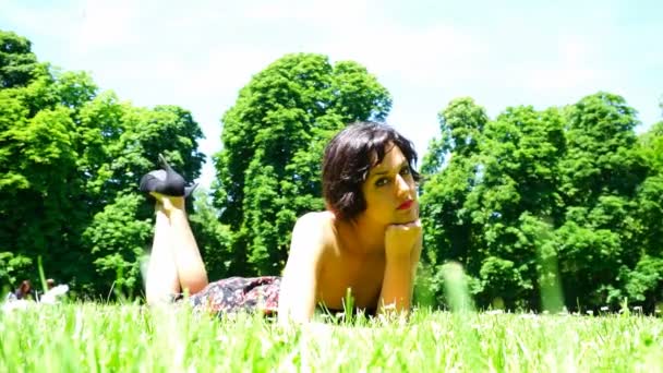 menina bonita com cabelo curto deitado no jardim público em parma - Filmagem, Vídeo
