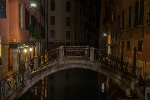 Włochy, Wenecja, długi most nad kanałem w mieście nocą - Zdjęcie, obraz