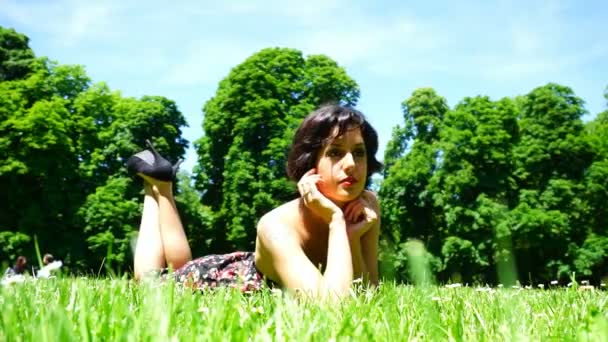menina bonita com cabelo curto deitado no jardim público em parma - Filmagem, Vídeo