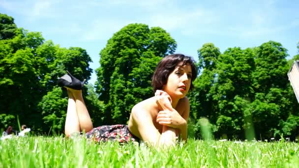 schönes Mädchen mit kurzen Haaren liegt im öffentlichen Garten in Parma - Filmmaterial, Video