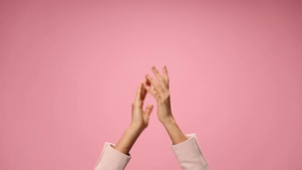 τα χέρια της γυναίκας παλαμάκια, δείχνοντας τα δάχτυλα και χειροκροτώντας σε ροζ φόντο - Πλάνα, βίντεο