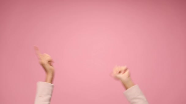 young woman holding hands in the air pointing fingers, moving and dancing on pink background - Footage, Video