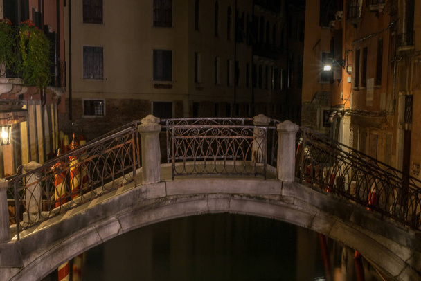 Italien, Venedig, eine Brücke mit einem Gebäude im Hintergrund bei Nacht - Foto, Bild