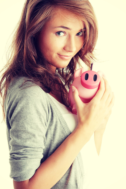 Woman standing with piggy bank - Foto, afbeelding