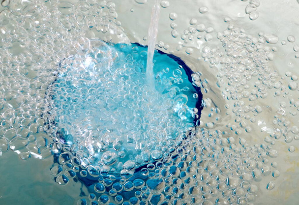 Água transbordante em um copo azul, vidro transbordante completo com água e bolhas - Foto, Imagem