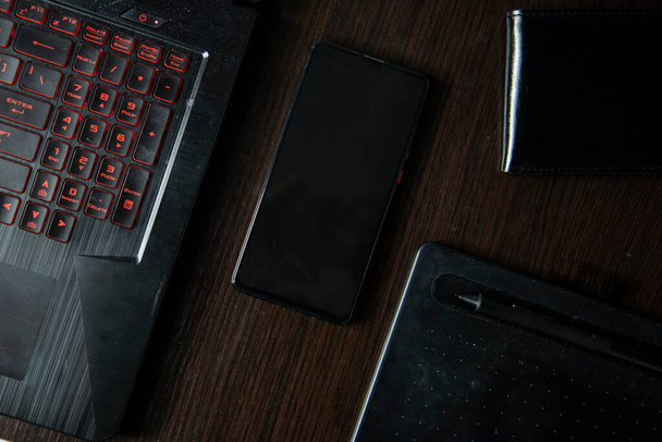 mobiele telefoon laptop tablet voor portemonnee ontwerp op een zwarte houten tafel zeer elegant en formeel - Foto, afbeelding