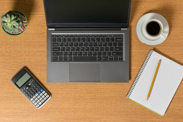 Vista superior de un espacio de trabajo con un portátil un bloc de notas con un lápiz y una taza de café. - Foto, Imagen