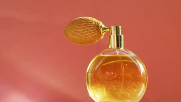 Kultainen hajuvesipullo ja loistavat valosoihdut, tyylikäs tuoksu tuoksu ylellisenä tuotteena kosmeettiselle ja kauneusbrändille  - Materiaali, video