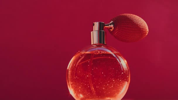 Vintage-Parfümflasche und leuchtende Lichterketten auf rotem Hintergrund, glamouröser Duftduft als Luxus-Parfümerieprodukt für Kosmetik- und Schönheitsmarken - Filmmaterial, Video
