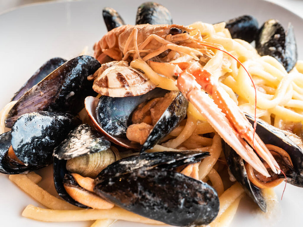assiette de spaghettis avec du poisson frais mélangé dans une douce soirée de printemps dans un restaurant italien sur la mer Méditerranée. avec crustacés et moules - Photo, image
