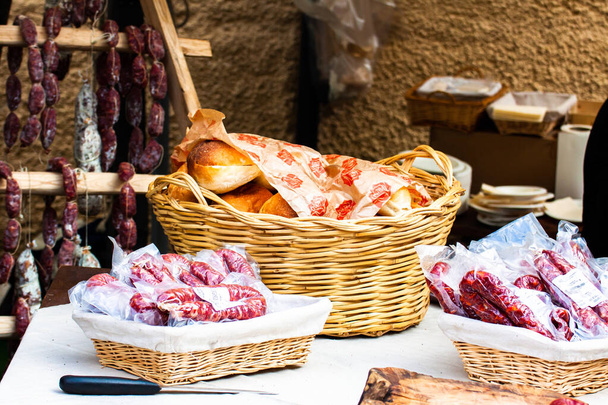 display of deli meats and gourmet gastronomy, salami, dried sausages and artisan bread, tasting in the street at the Italian mountain festival - Zdjęcie, obraz