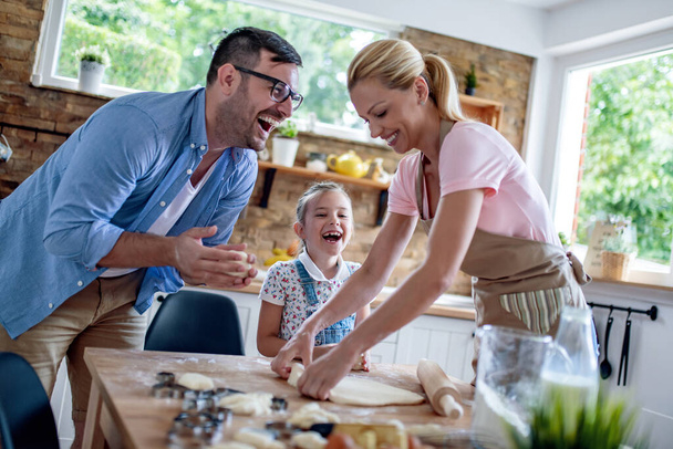 Щасливий батько, мати і дочка роблять випічку вдома на кухні
. - Фото, зображення
