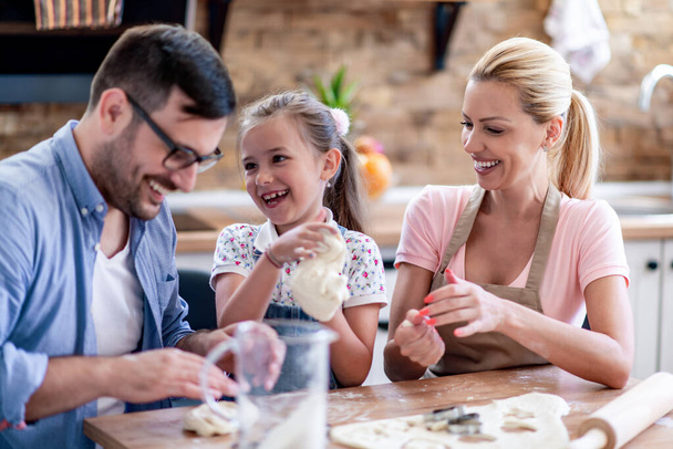 Boldog család sütit süt otthon a konyhájukban. Család, szerelem, emberek, szabadidő és életmód koncepció. - Fotó, kép