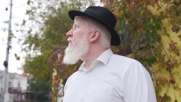 close-up van een oudere man met albinisme in wit shirt en hoed. - Video