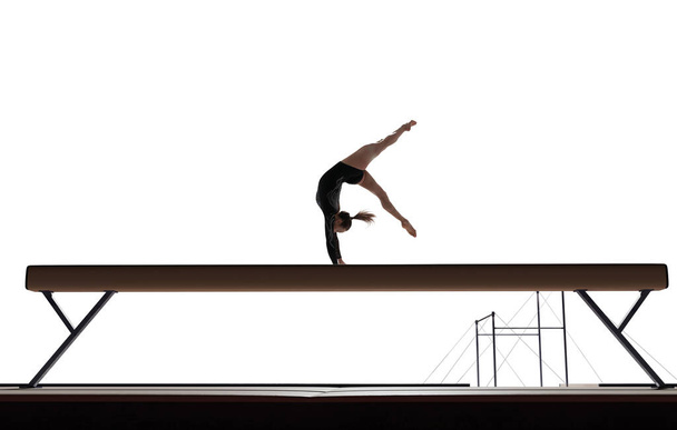 Female gymnast doing a complicated trick in a professional arena - Photo, Image