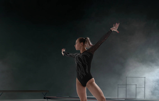 Profesyonel bir arenada kadın jimnastikçi karmaşık bir numara yapıyor. - Fotoğraf, Görsel