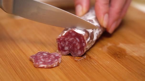 Young woman cutting sausage on wooden board. - Footage, Video