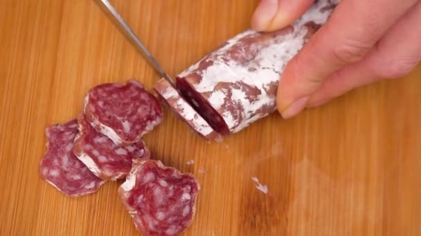 Women's hands cutting sausage goods with knife on chopping board. - Footage, Video
