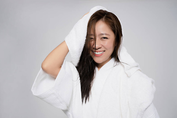 Asiatin benutzt ein Handtuch, um ihre Haare nach der Dusche zu trocknen. Auf weißem Hintergrund. - Foto, Bild