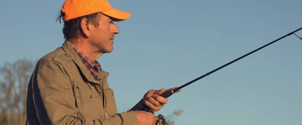 Rybářský prut kolo detailní up, muž rybaření s krásným západem slunce. - Fotografie, Obrázek